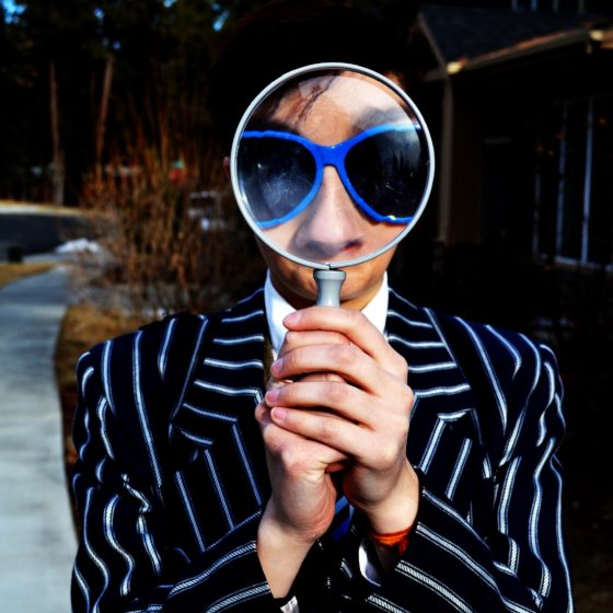 Person holding a magnifying glass in front of their face