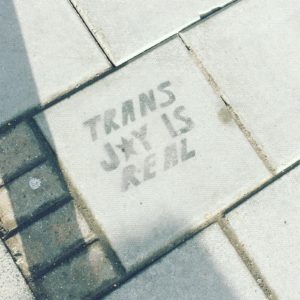 A painted sign on a pavement in Cambridge, UK declare ‘Trans joy is real’